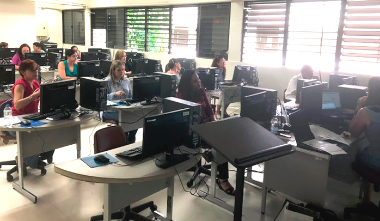 Varios miembros del personal tomando el Taller Blog para facilitar la educación y crear identidad digital sentados en un laboratorio de computadoras